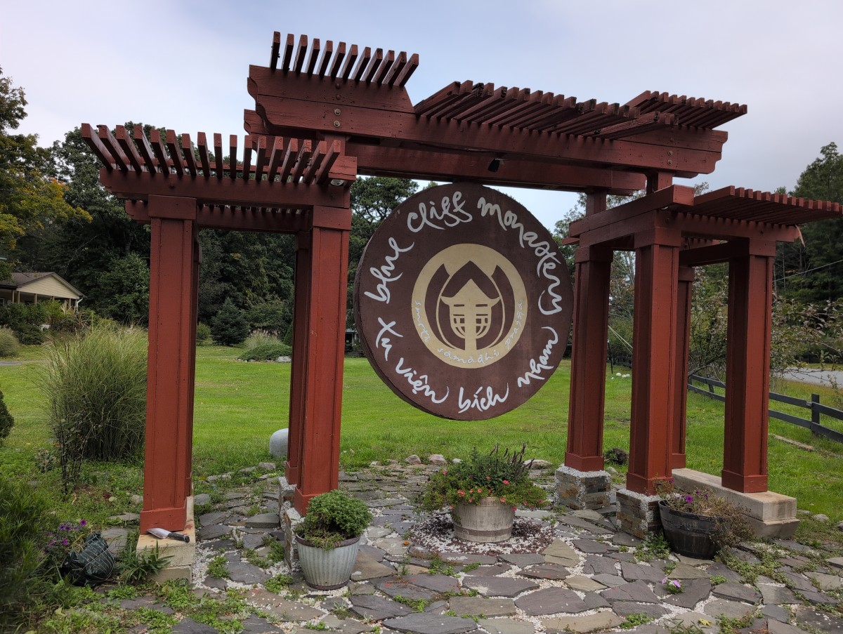 A large wooden circular sign that says Blue Cliff Monastery Tu viện Bích Nham